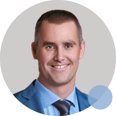 Dr. Benjamin Hewitt, an orthopaedic surgeon, smiles in a blue suit and tie, symbolizing his commitment to excellence in surgery.