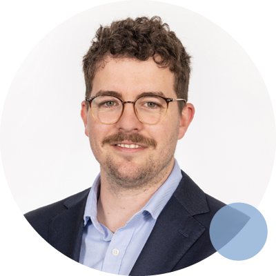 Dr. Brynn Bellinge, an Occupational Physician Registrar, smiles confidently in a suit and tie, showcasing professionalism.