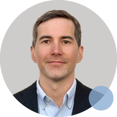 A man in a suit and tie stands beside a blue circle, representing Dr. Michael Perret, an orthopaedic and hand surgeon.